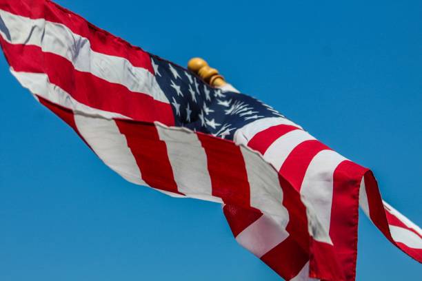 istock American flag waving in the breeze against a bright blue sky 1168307521