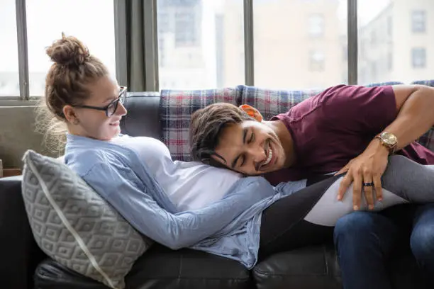 Photo of Grinning Young Man Listening to Pregnant Girlfriend's Belly