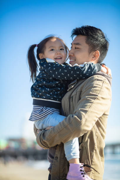 istock Father Cuddling Daughter on the Beach 1168309153