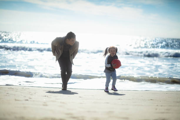 istock Laughing Father Playing with Little Girl on Beach 1168309160