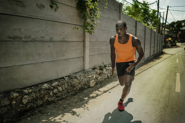 urban runner workout . Young attractive and athletic black African American man running outdoors on asphalt road training hard jogging in sport sacrifice commitment and healthy lifestyle concept entrenamiento de corredor urbano. joven atractivo y atlético negro afroamericano corriendo al aire libre en el entrenamiento de asfalto de carretera duro trotando en el compromiso de sacrificio deportivo y concepto de estilo de vida saludable