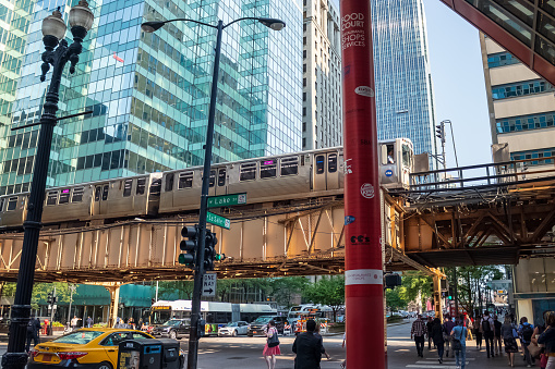 Chicago, IL / USA - 7/24/19: Corner of Lake and LaSalle Street where commuters walk and ride the el train on elevated track above Chicago Loop  during summer