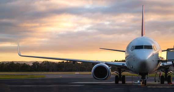 Sunset view of airplane on airport runway under dramatic sky in Hobart,Tasmania, Australia. Aviation technology and world travel concept.