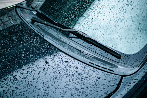 Wet car windshield and hood in rainy season.