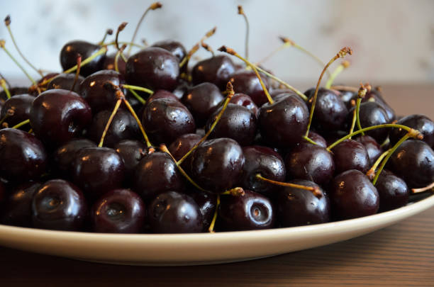 istock Wet chilled cherries with peduncles on plate on table 1168334300