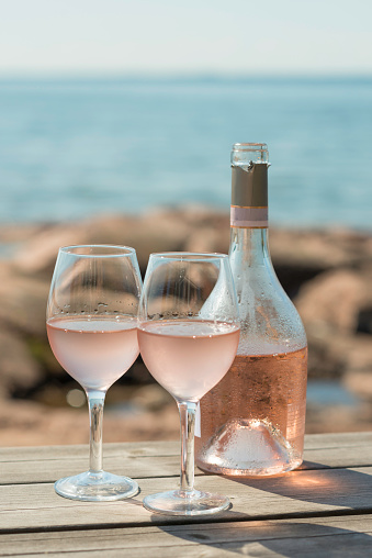 Rose wine glasses on sunny terrace by the seaside in summer
