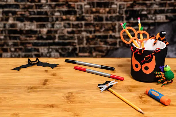 Halloween Crafting with a spooky pencil cup and some pipe-cleaner creatures.  There is plenty of Negative Space for copywriting on the Vintage Brick background and on the table surface.