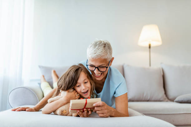 santa's little helper is bringing in the gifts - grandmother giving gift child imagens e fotografias de stock