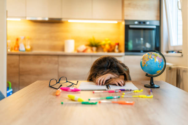 All this studying has exhausted her Lazy student girl at home, she is resting with her face down on the school book, education and childhood concept. Close up of an adorable little girl sleeping on the table after studying doing homework tired sleepy exhausted educational intelligence smart learning childhood family parenting concept. face down stock pictures, royalty-free photos & images