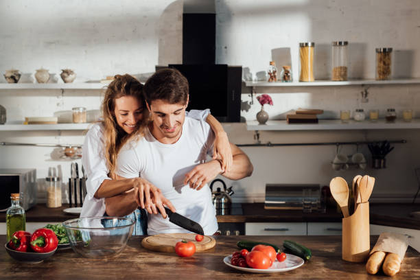 istock happy couple smiling while cooking together in kitchen 1168348355
