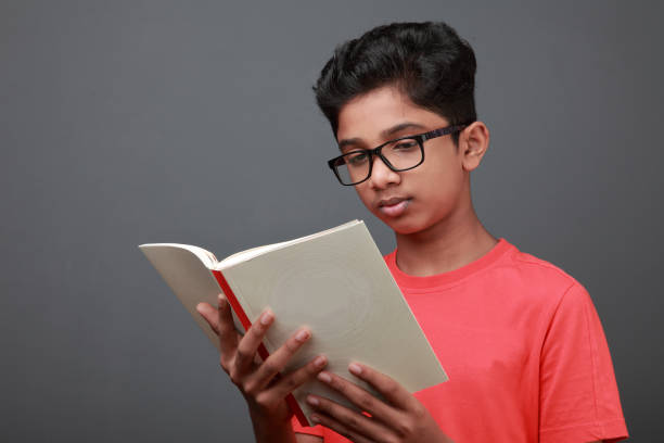 boy holds a book and reads it - facial expression child asia asian and indian ethnicities imagens e fotografias de stock