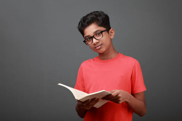 Boy looks as he holds a book in hand