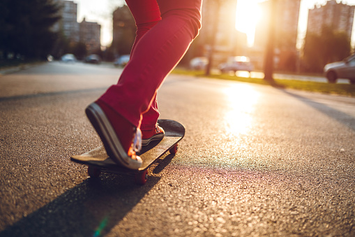 Caucasian skater girl skateboarding outdoor on street at a sunny day.