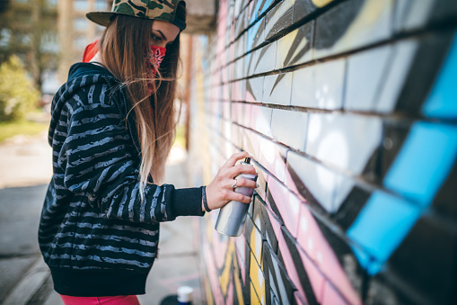 Graffiti female artist painting outdoor.