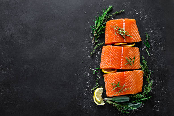 istock Salmon. Fresh raw salmon fish fillet with cooking ingredients, herbs and lemon on black background, top view 1168356706
