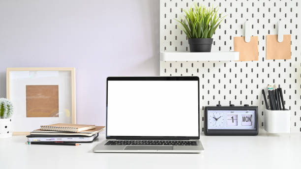 istock Laptop, pegboard and office supplies on workspace table with empty monitor computer. 1168364123