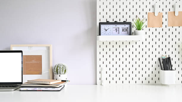istock Copy space mockup laptop, pegboard, photo frame, and office supply on white table office. 1168364164