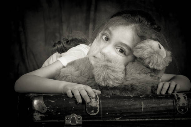Child hugging teddy bear and smiling at camera isolated on white