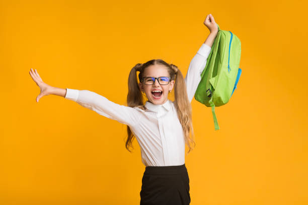 istock Carefree Elementary School Girl Posing With Backpack On Yellow Background 1168366352