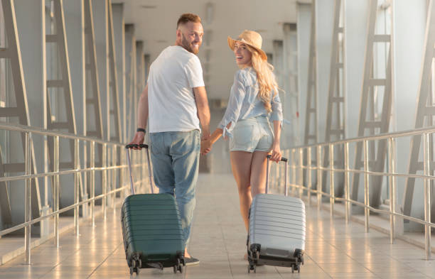 istock Loving couple walking with suitcases at airport 1168366607