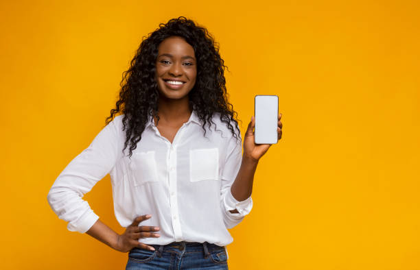 最新のスリムな携帯電話を示す陽気な黒人女性 - 見せる ストックフォトと画像