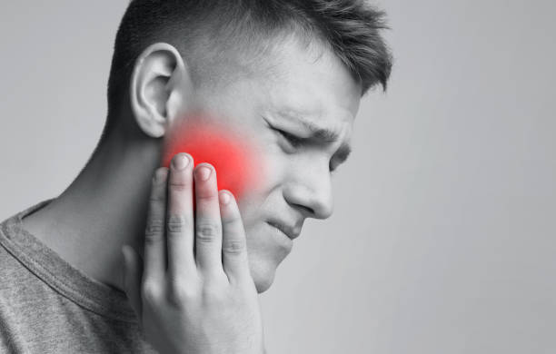 Young man suffering from strong toothache, monochrome photo Dental problem. Young man suffering from strong toothache, monochrome photo with red inflamed zone, free space jaw pain stock pictures, royalty-free photos & images