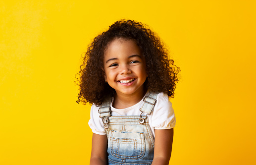 Feliz niña afroamericana sonriente, fondo amarillo photo