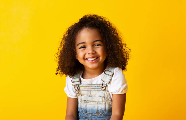 feliz niña afroamericana sonriente, fondo amarillo - etnia latinoamericana fotos fotografías e imágenes de stock