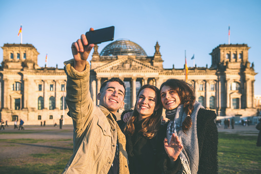 three young people taking selfie in front of Berlin Reichstag