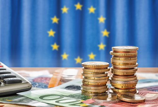 Billetes y monedas frente a la bandera de la Unión Europea photo
