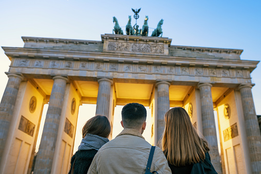 rear view on young man and two womanin front of Brandenburger Tor in golden light