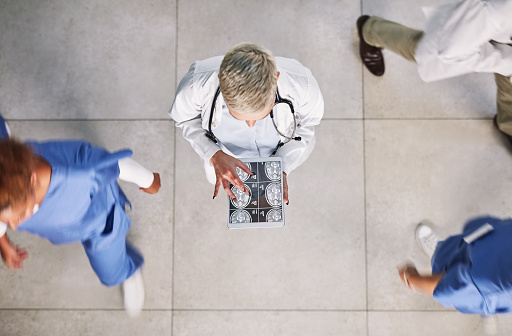 High angle shot of a doctor looking at x-rays on a digital tablet in a busy hospital