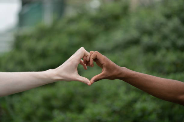 istock Light and dark-skinned men making heart with hands 1168375763