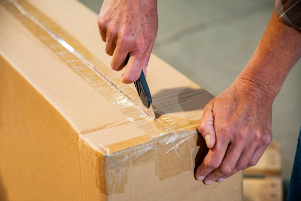 istock An industrial workplace warehouse safety topic. A female cutting a box using a utility knife. 1168378912