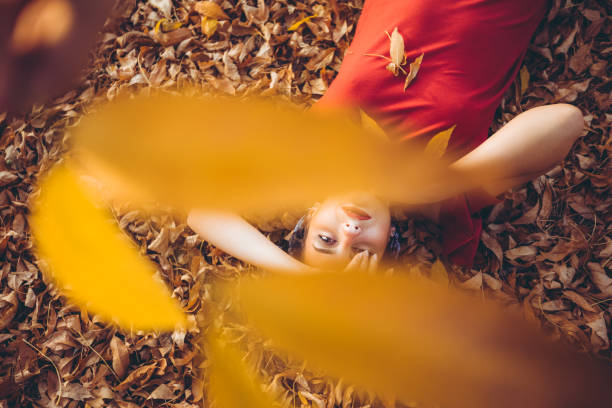 Young beautiful caucasian woman lying on autumn leaves.