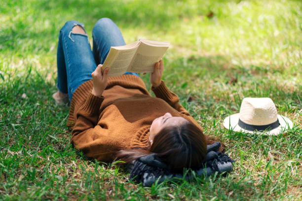 istock woman lying and reading a book in the park 1168385363