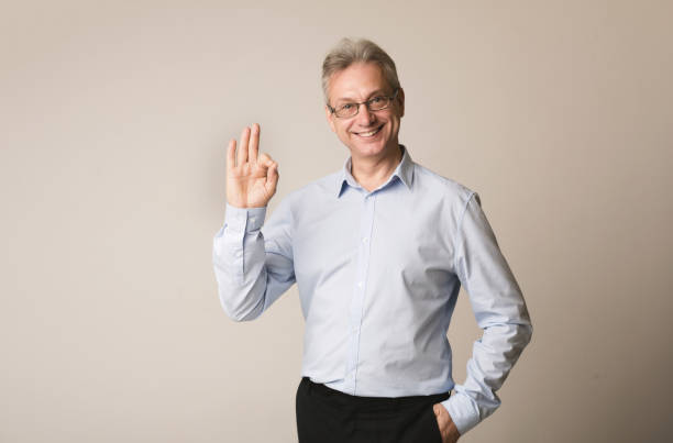 istock Senior businessman showing okay gesture, grey background 1168385980