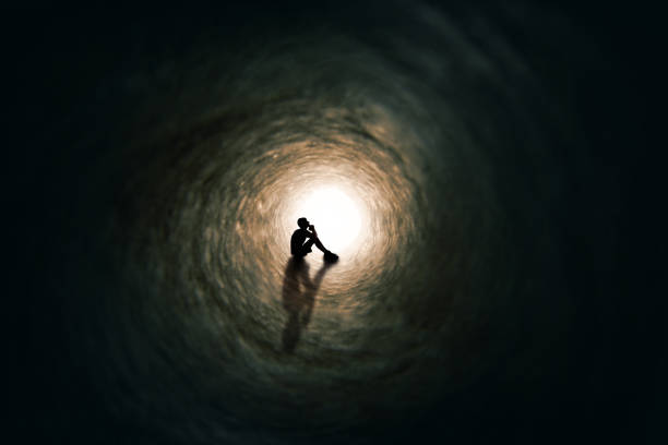 Teen Boy Silhouette Far Away Praying in Tunnel stock photo