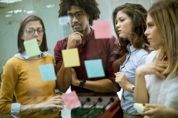 istock Young business people discussing in front of glass wall using post it notes and stickers 1168391614
