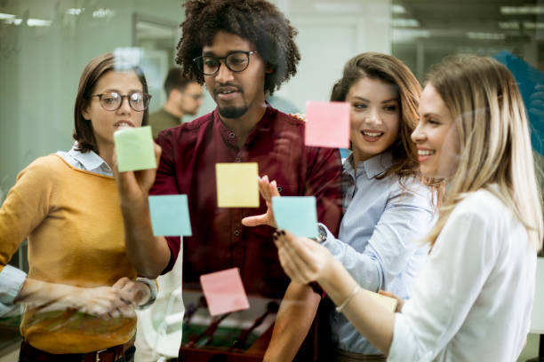 istock Young business people discussing in front of glass wall using post it notes and stickers 1168391642