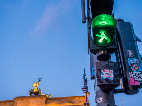 two icons of Berlin; Branderburger tor and the Ampelmann.  Typical and famous pedestrian traffic light of Berlin with walking green man 