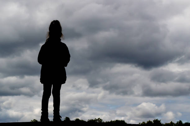 istock girl stands against a dark menacing sky 1168392392