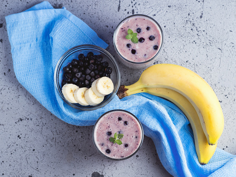 Two glass glasses of blueberry smoothie with banana on the table