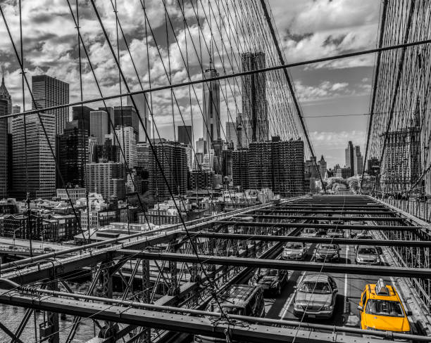Manhattan skyline and  traffic on Brooklyn Bridge . In the background is seen East River and Lower Manhattan skyline against blue sky after sunset. On the left side are seen  new One World Trade Center - Freedom Tower and Beekman Tower the tallest residential tower in world, designed by Frank Gehry. New York City, horizontal orientation, America, USA.