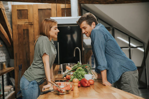 istock Beautiful young couple smiling while cooking in kitchen at home 1168398651