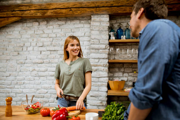 istock Beautiful young couple smiling while cooking in kitchen at home 1168398682