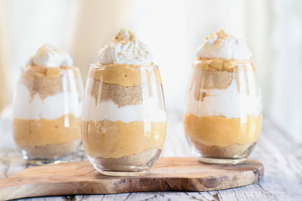 Pumpkin trifle dessert with whipped cream Homemade pumpkin trifle dessert made from pumpkin puree, cream cheese, cookie crumbs and whipped cream. Extreme selective focus with blurred background. trifle stock pictures, royalty-free photos & images