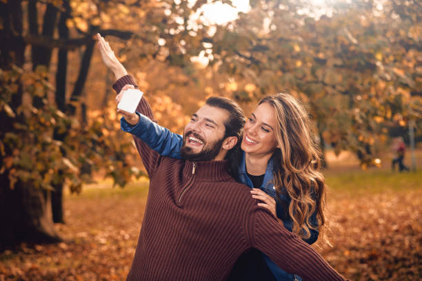 istock Young couple using cellphone in autumn colored park. 1168405268