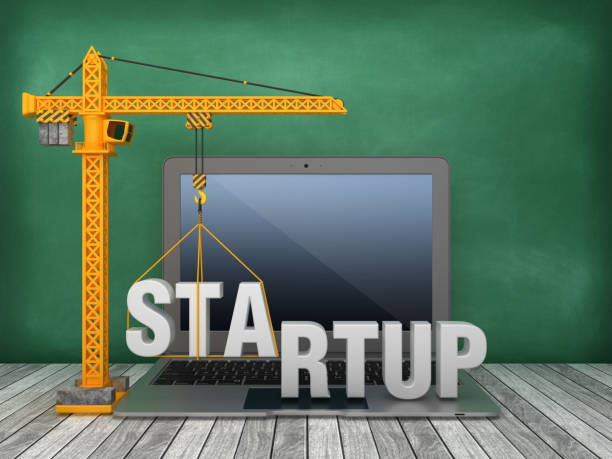 istock Tower Crane and Laptop with STARTUP Word on Chalkboard Background - 3D Rendering 1168408010