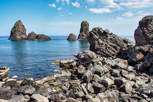 A Cyclops island, basaltic rock fomation, viwed from the port of Aci Trezza, Catania, Sicily, Italy.